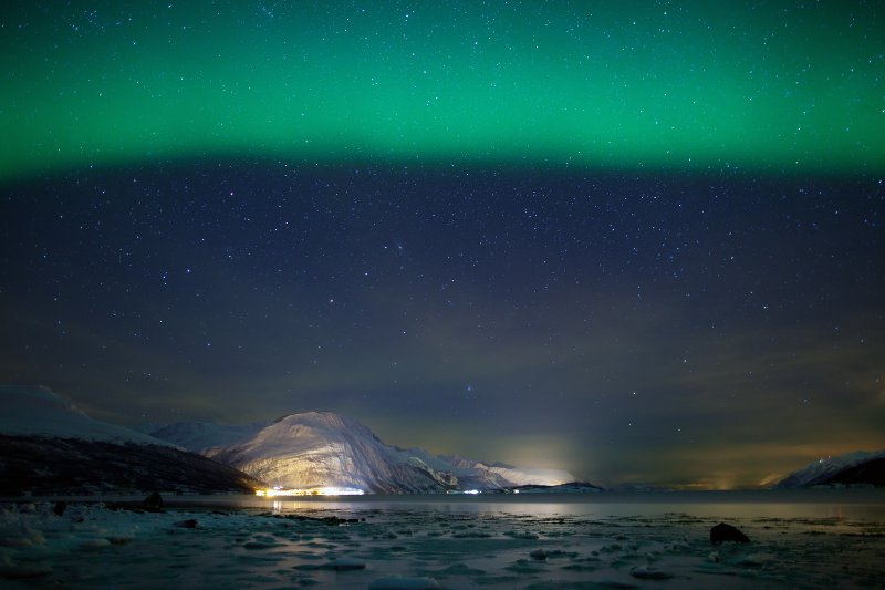 Green aurora borealis over a frozen fjord© spumador